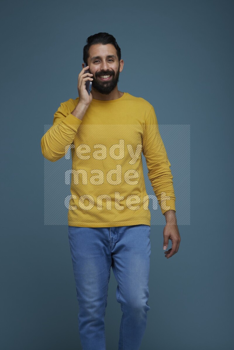 A man having a calling in a blue background wearing a yellow shirt