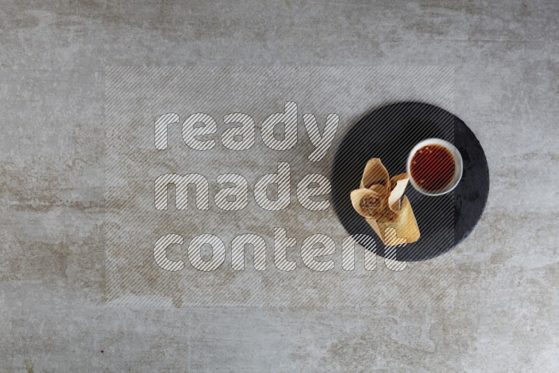 wonton cups with soy sauce ramkin on circle slate on grey textured counter top
