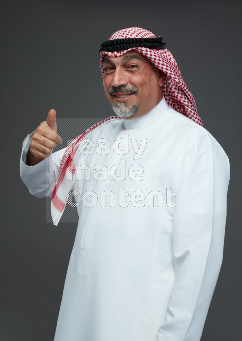Saudi man with shomag Standing Interacting with the camera on gray background