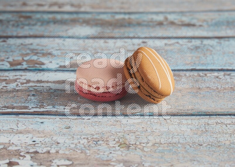 45º Shot of of two assorted Brown Irish Cream, and Pink Litchi Raspberry macarons on light blue background