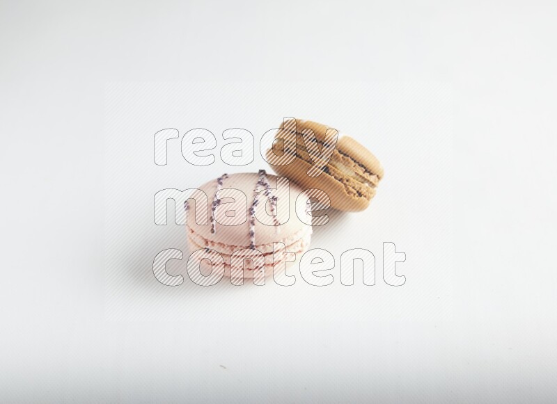 45º Shot of of two assorted Brown Irish Cream, and pink orange blossom macarons on white background