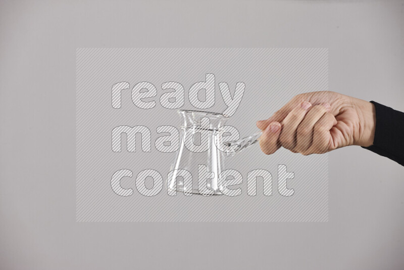 A woman in black abaya holding different glassware in different positions
