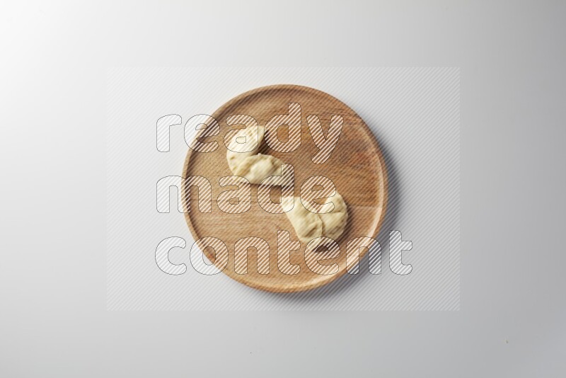 Four Sambosas on a wooden round plate on a white background
