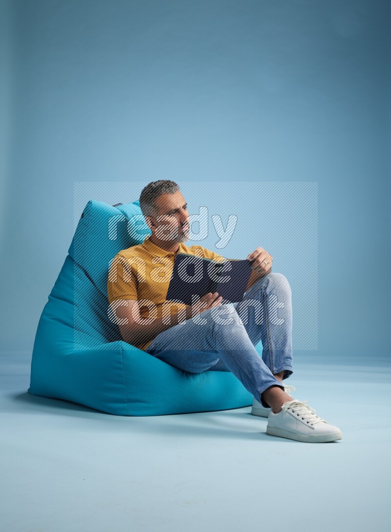 A man sitting on a blue beanbag and reading a book