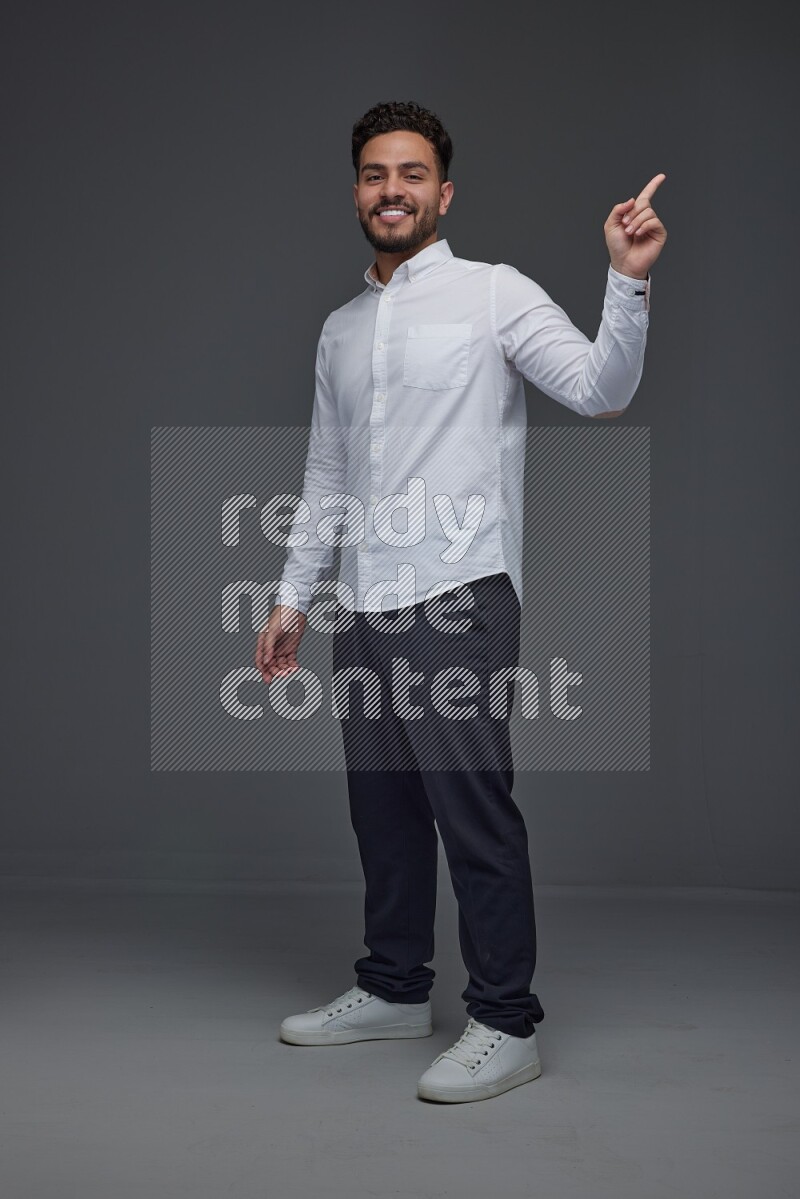 A man wearing smart casual standing and making multi hand gestures eye level on a gray background