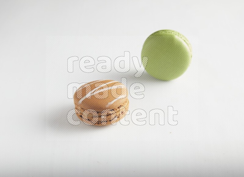 45º Shot of of two assorted Brown Irish Cream, and Green Pistachio macarons on white background