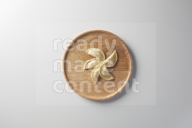 Five Sambosas on a wooden round plate on a white background