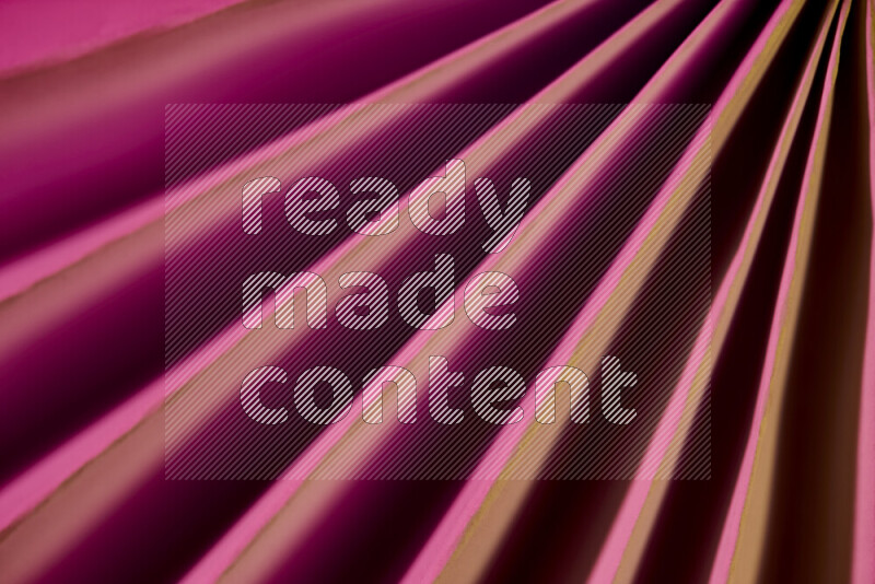 An image presenting an abstract paper pattern of lines in pink and gold tones