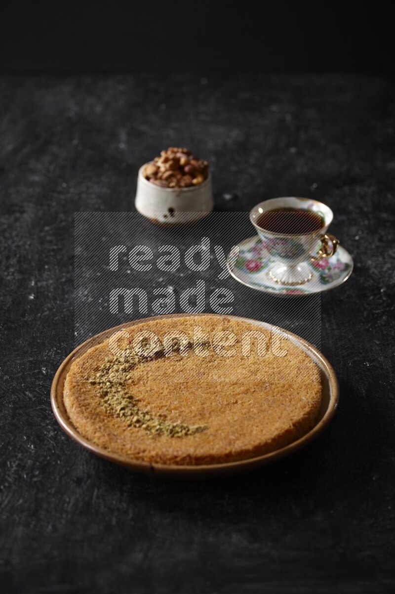 Konafa with nuts and tea in a dark setup
