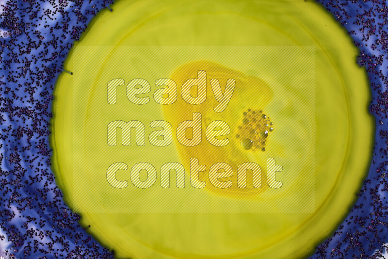 A close-up of sparkling purple glitter scattered on swirling blue and yellow background