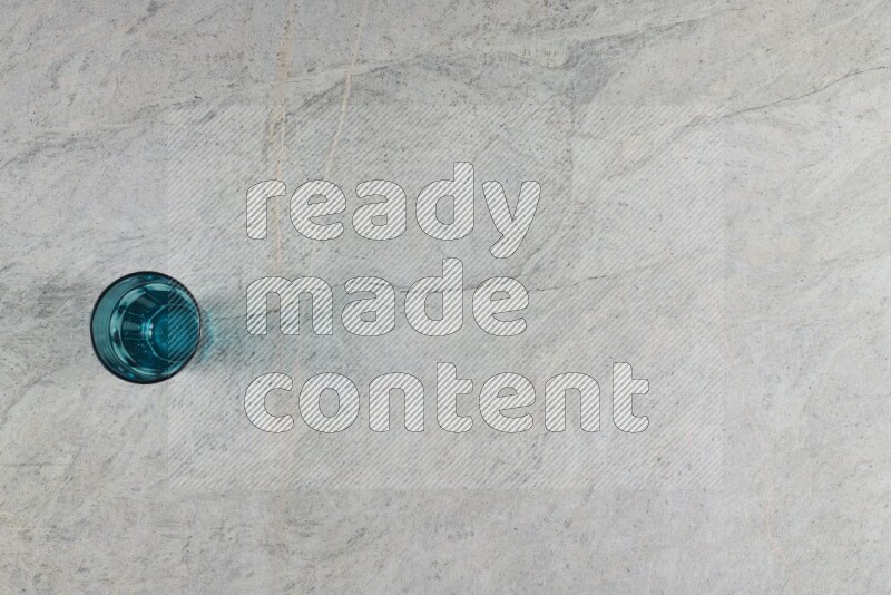 A turquoise glass cup on grey marble background