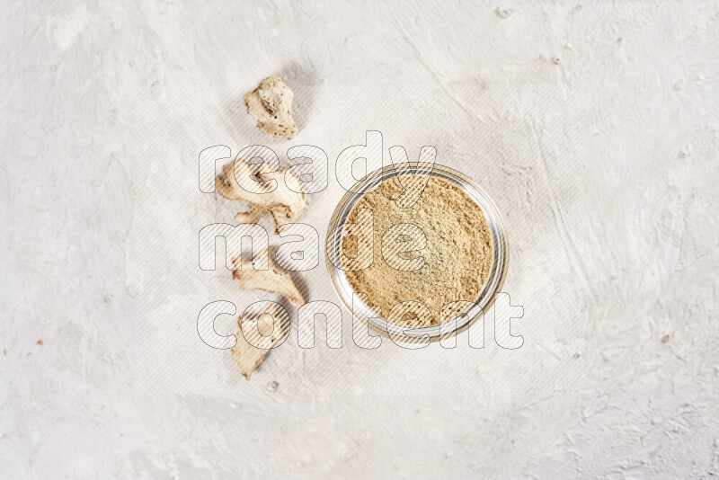 A glass bowl full of ground ginger powder on white background