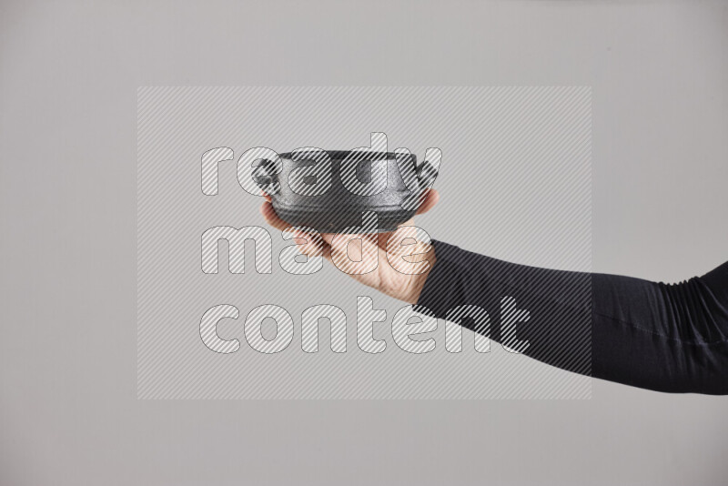 A woman in black abaya holding different pottery essentials in different positions
