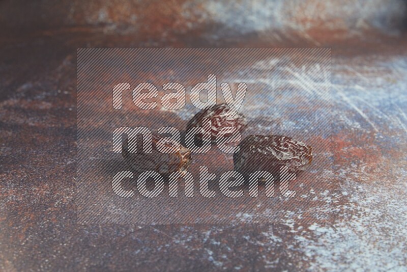 three madjoul dates on a rustic reddish background