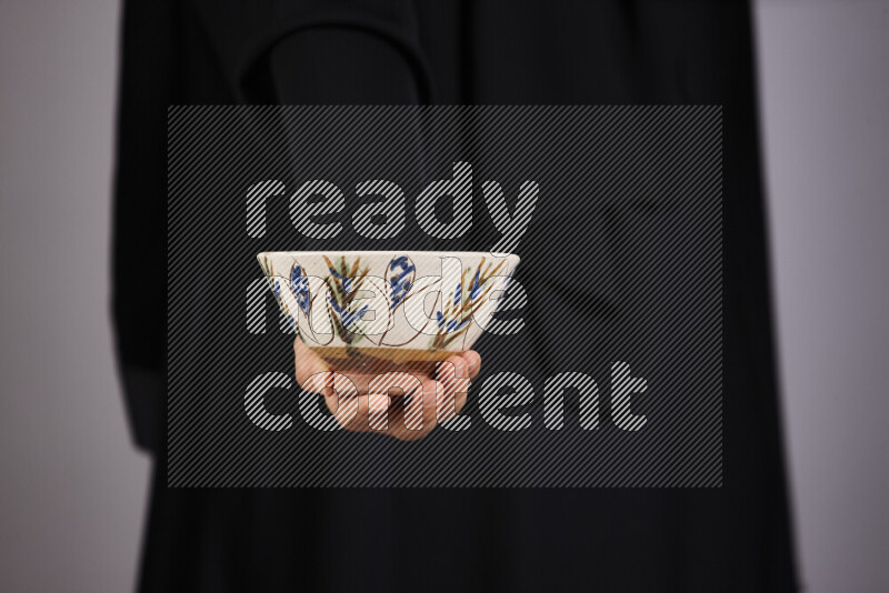 امرأة ترتدي عباءة سوداء تحمل أدوات فخارية مختلفة في أوضاع متعددة