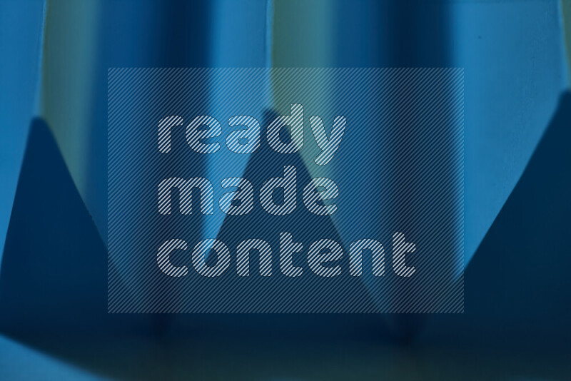 A close-up abstract image showing sharp geometric paper folds in blue gradients