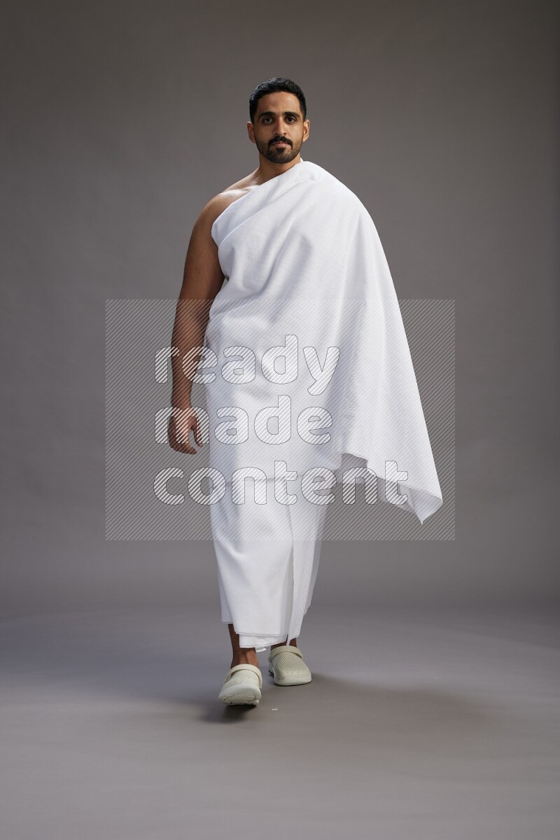 A man wearing Ehram Standing Interacting with the camera on gray background