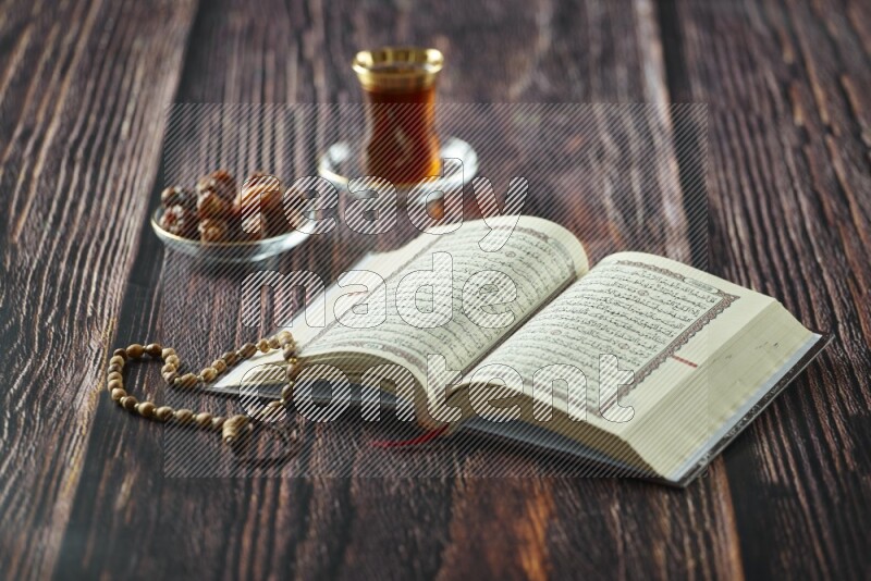 Quran with dates, prayer beads and different drinks all placed on wooden background