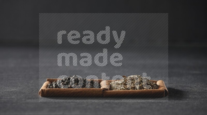 مربعان من أعواد القرفة ممتلئان بحبوب الفلفل الأسود وحبوب الكمون علي خلفية سوداء