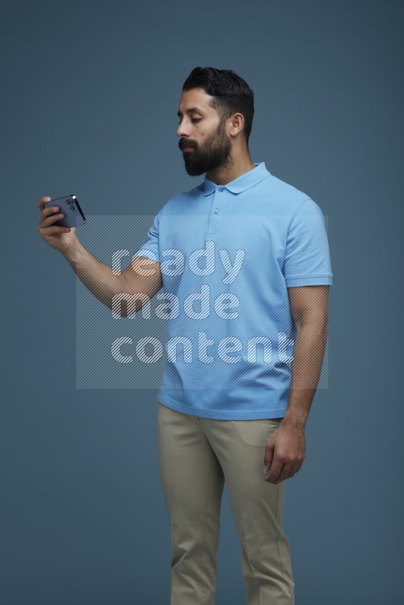 A man Watching a movie on his phone in a blue background wearing a Blue shirt