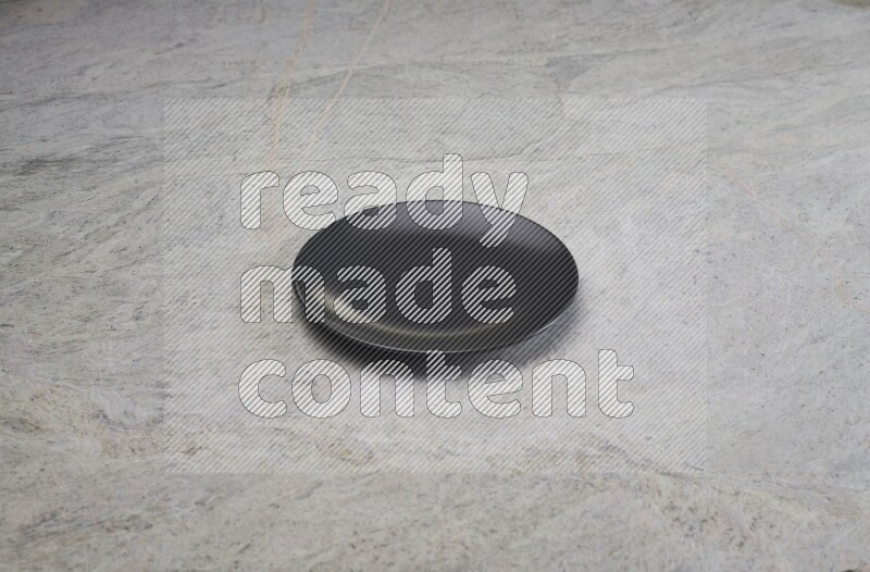 A black ceramic circular plate on grey marble background