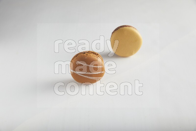 45º Shot of of two assorted Brown Irish Cream, and Yellow, and Brown Chai Latte macarons on white background