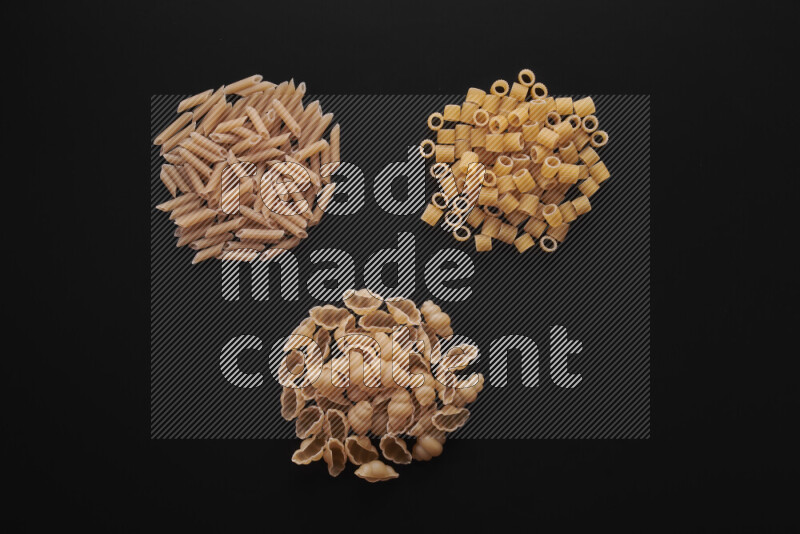 Different pasta types in bunches on black background