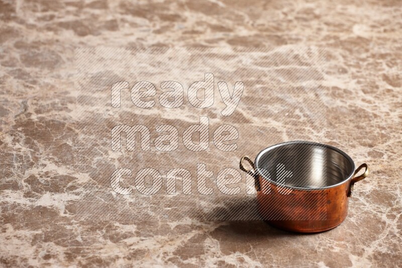 A small copper pot on beige marble background