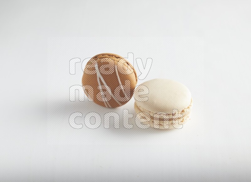 45º Shot of of two assorted Brown Irish Cream, and White Caramel fleur de sel macarons on white background