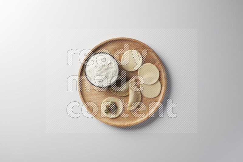 two closed sambosas and one open sambosa filled with meat while flour aside in a wooden dish on a white background