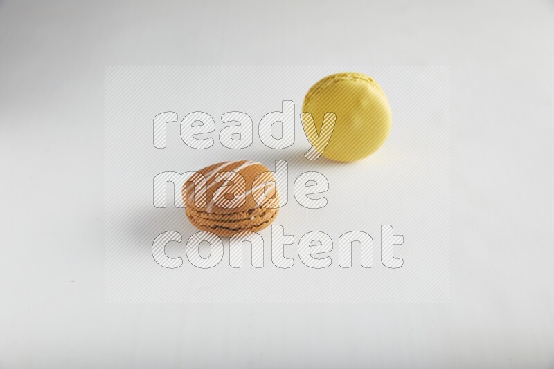 45º Shot of of two assorted Brown Irish Cream, and Yellow Lemon macarons on white background