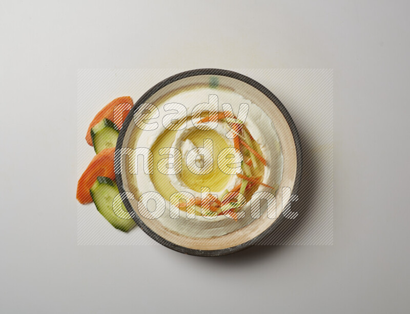 Lebnah garnished with sliced carrots &cucumber in a pottery plate on a white background