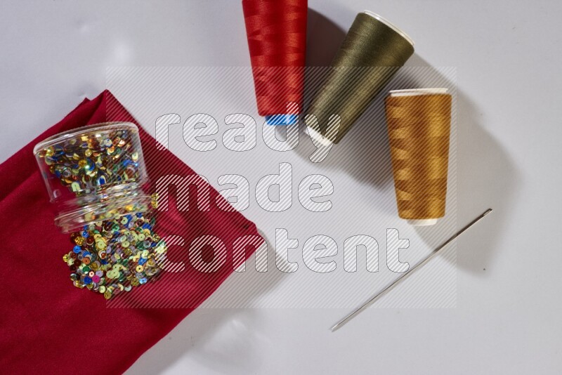 Multicolored fabrics with sewing supplies on grey background