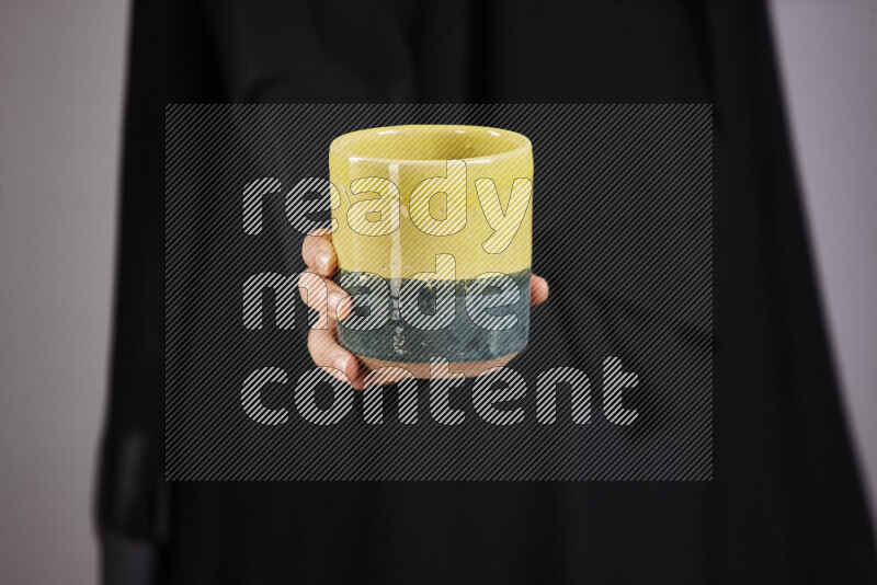 A woman in black abaya holding different pottery essentials in different positions