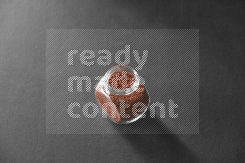 A glass spice jar full of garden cress on black flooring