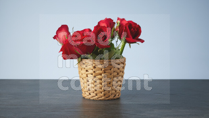 Vibrant red roses in a wicker basket on black marble background