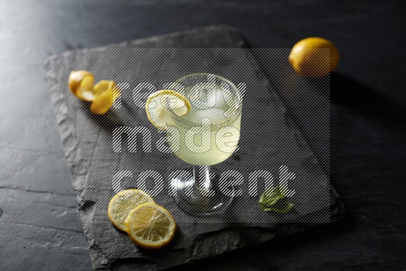 A glass of lemon juice with a lemon slice on black background