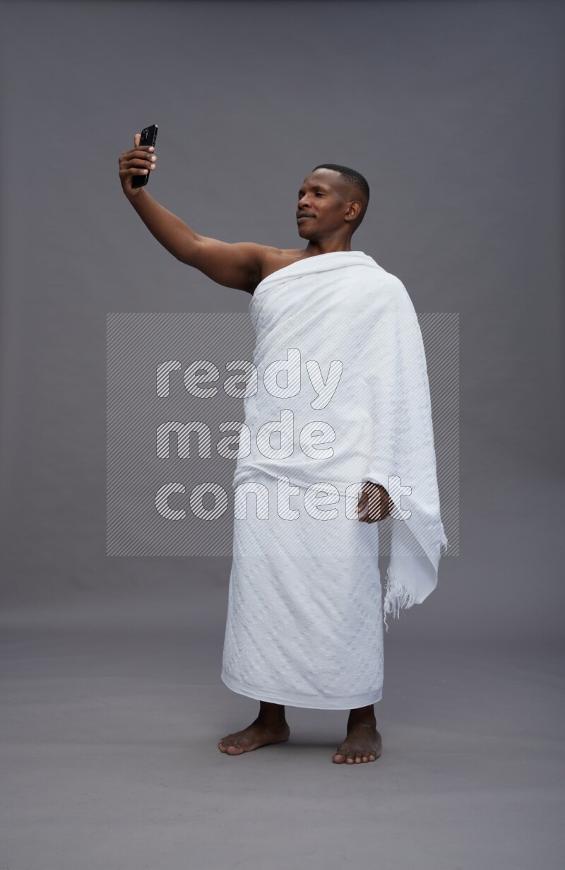 A man wearing Ehram Standing taking selfie on gray background