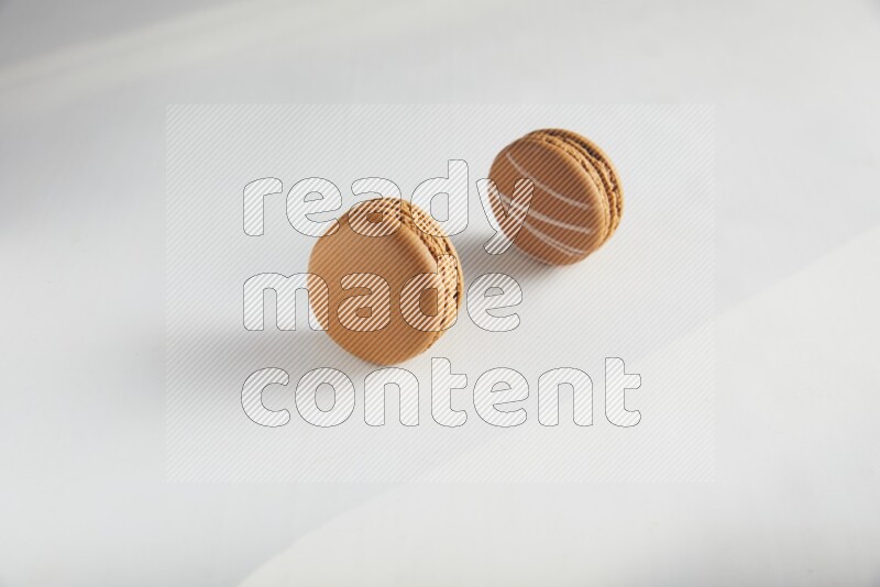 45º Shot of of two assorted Brown Irish Cream, and Brown Maple Taffy macarons  on white background