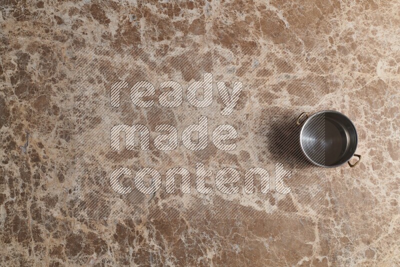 A small copper pot on beige marble background