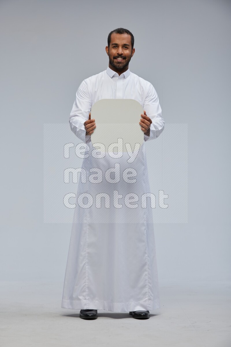Saudi man wearing Thob standing holding social media sign on Gray background