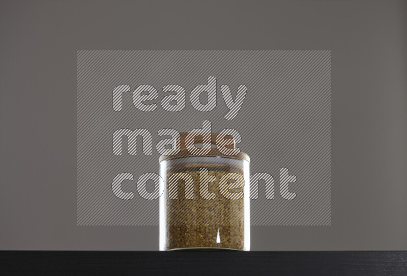Coarse bulgur in a glass jar on black background