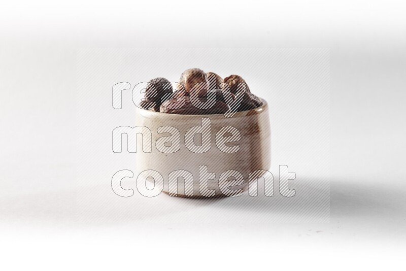 Dates in a beige pottery bowl on white background