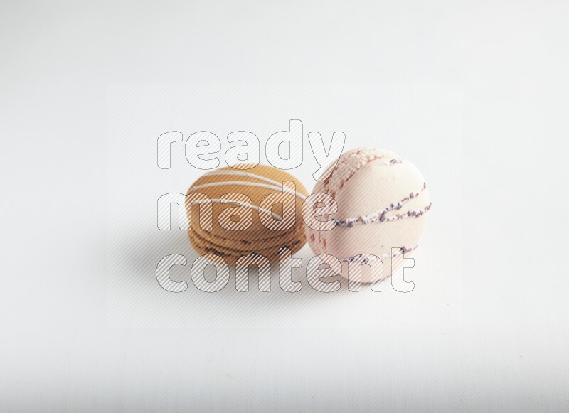 45º Shot of of two assorted Brown Irish Cream, and pink orange blossom macarons on white background