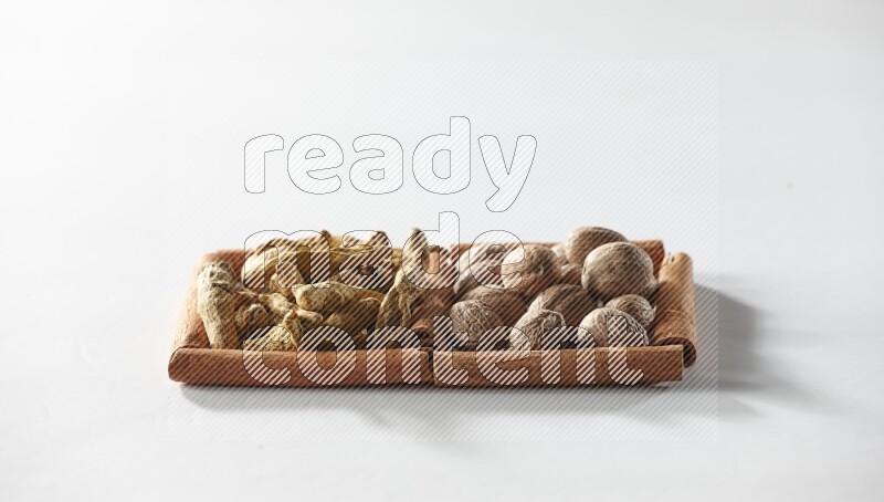 2 squares of cinnamon sticks full of turmeric fingers and nutmegs on white flooring