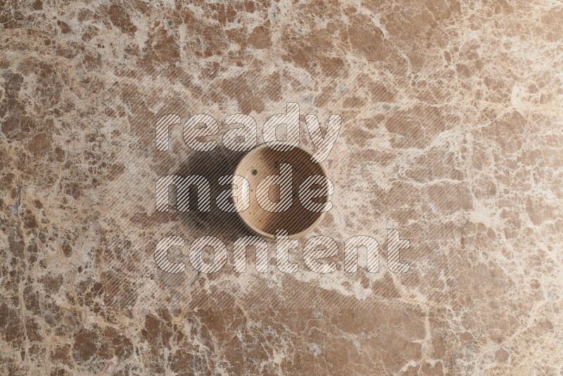 A multicolored pottery bowl on beige marble background
