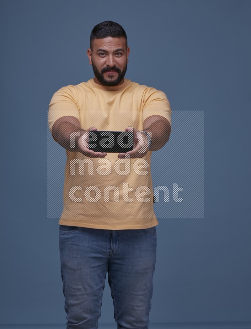 A man Showing His Smart Phone on Blue Background wearing Orange T-shirt