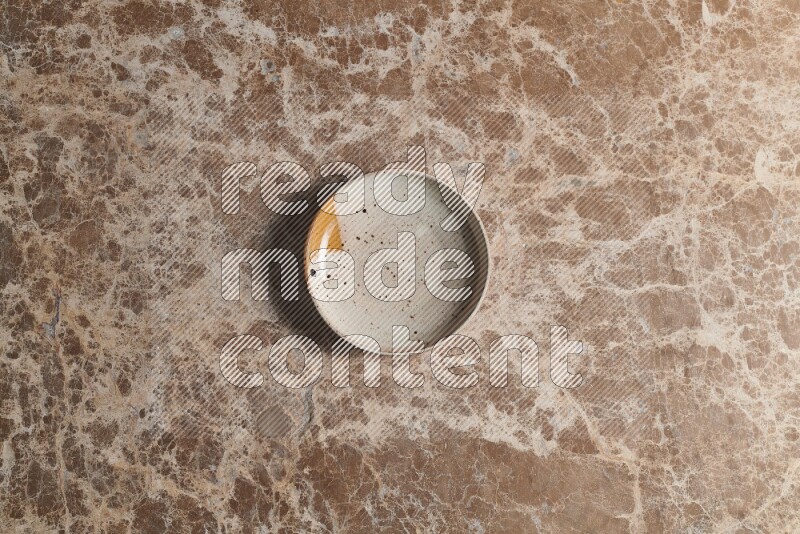 A multicolored pottery bowl on beige marble background
