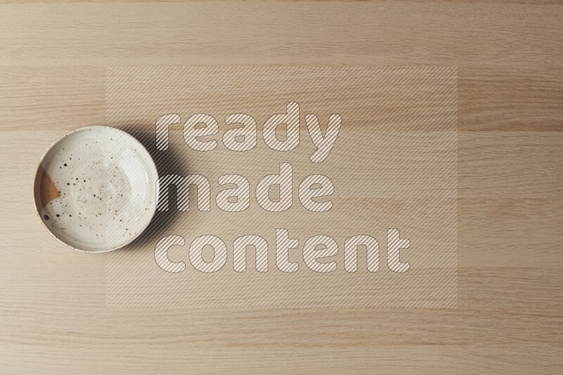 صحن فخاري متعدد الألوان على خلفية خشبية فاتحة