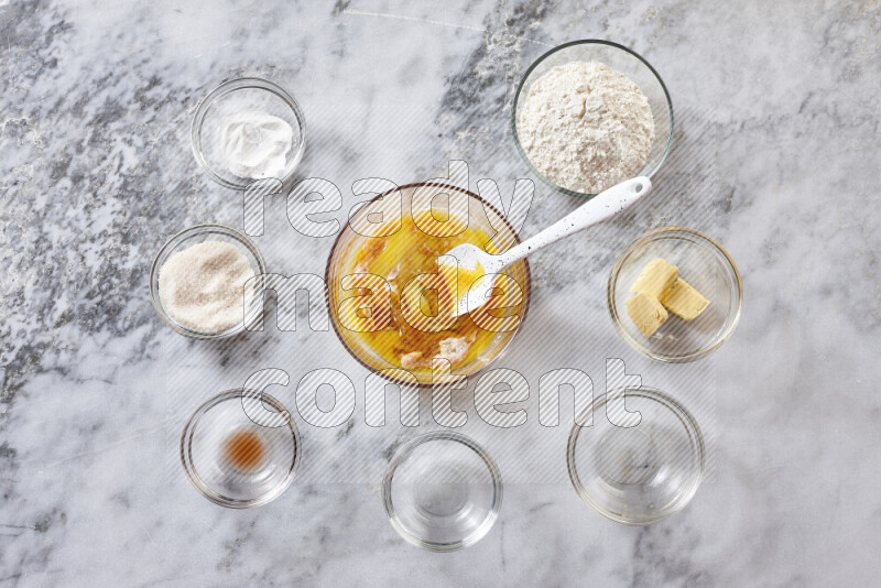 Cookies step by step with its ingredient, flour, butter, brown sugar, egg, vanilla extract, white sugar, chocolate chips and baking soda on grey marble background
